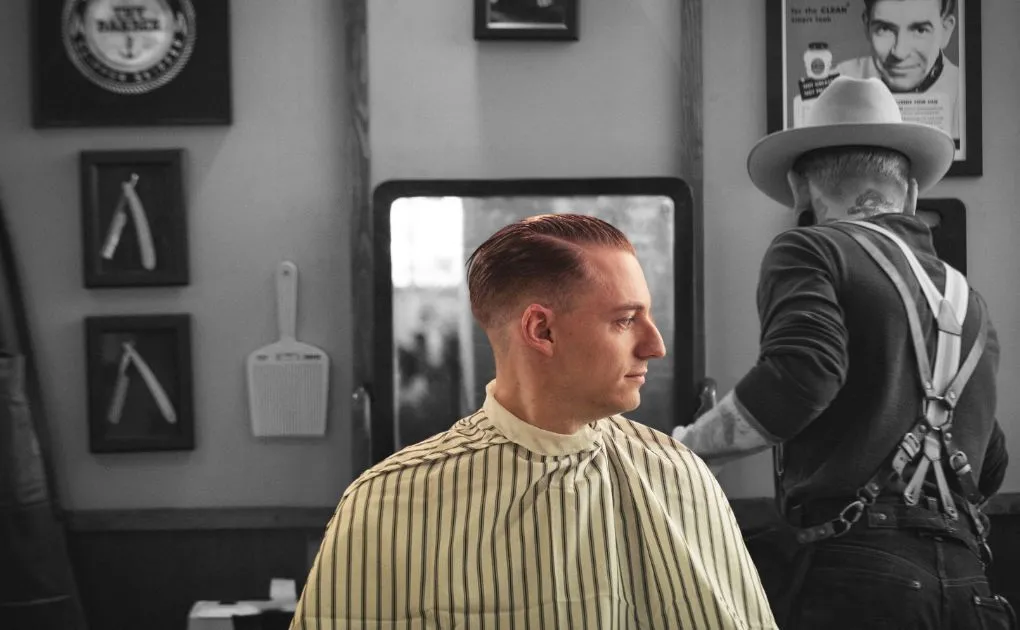 A man sitting in a barber shop getting his hair cut.