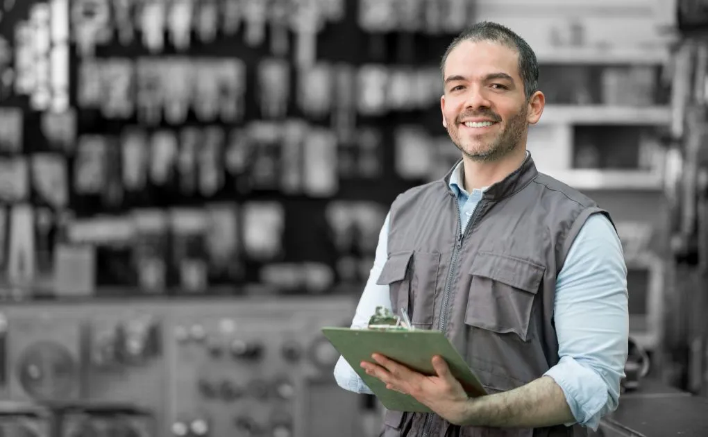 A man in a factory holding a clipboard.