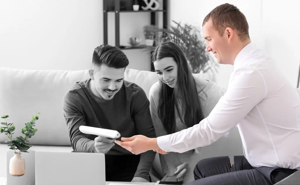 A man and a woman sitting on a couch looking at a remote control.