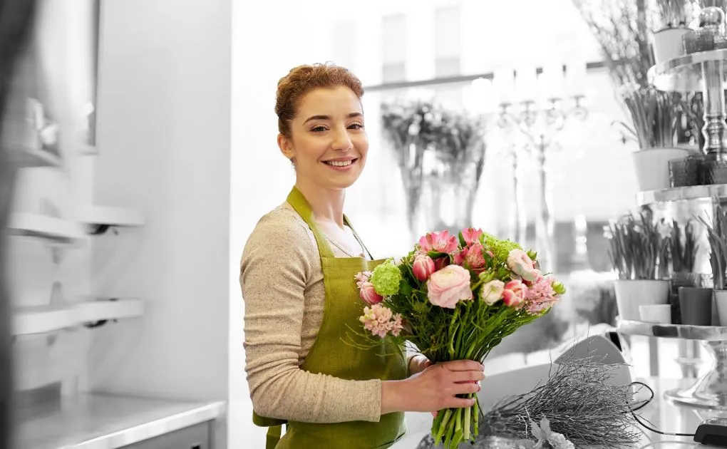 A woman in an apron holding a bouquet of flowers.