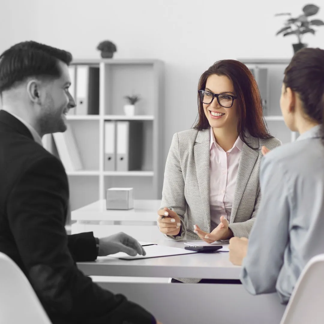 A woman sitting at a table talking to two men.