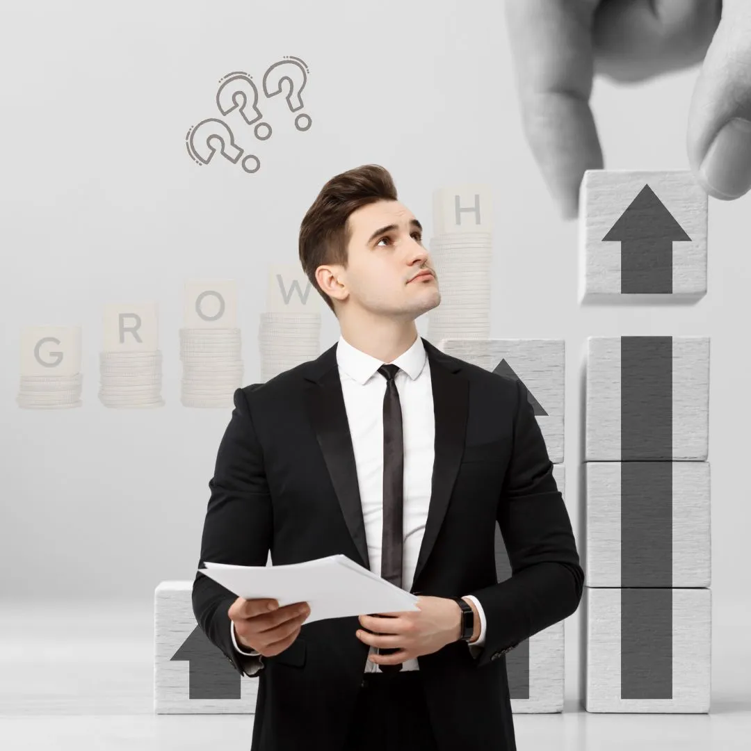 A man in a suit and tie standing in front of stacks of blocks with question.
