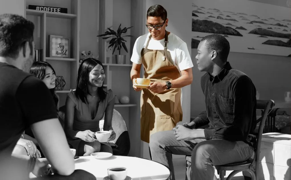 A man in an apron serving food to a group of people.