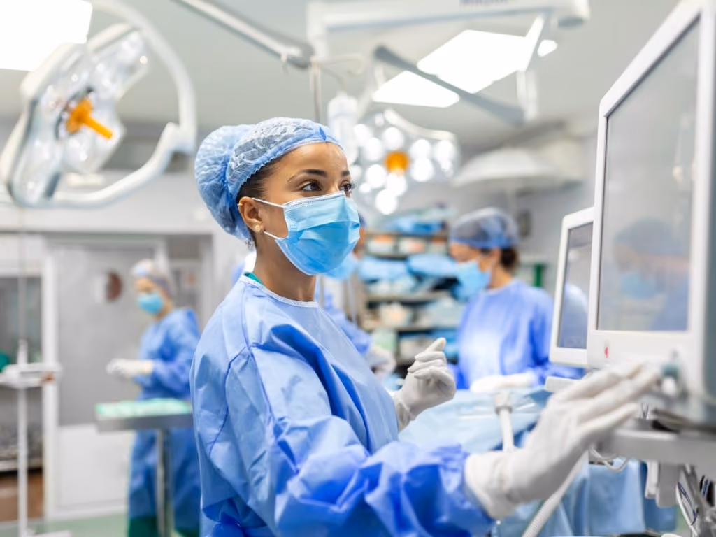 anesthetist working in operating theatre wearing protecive gear checking monitors