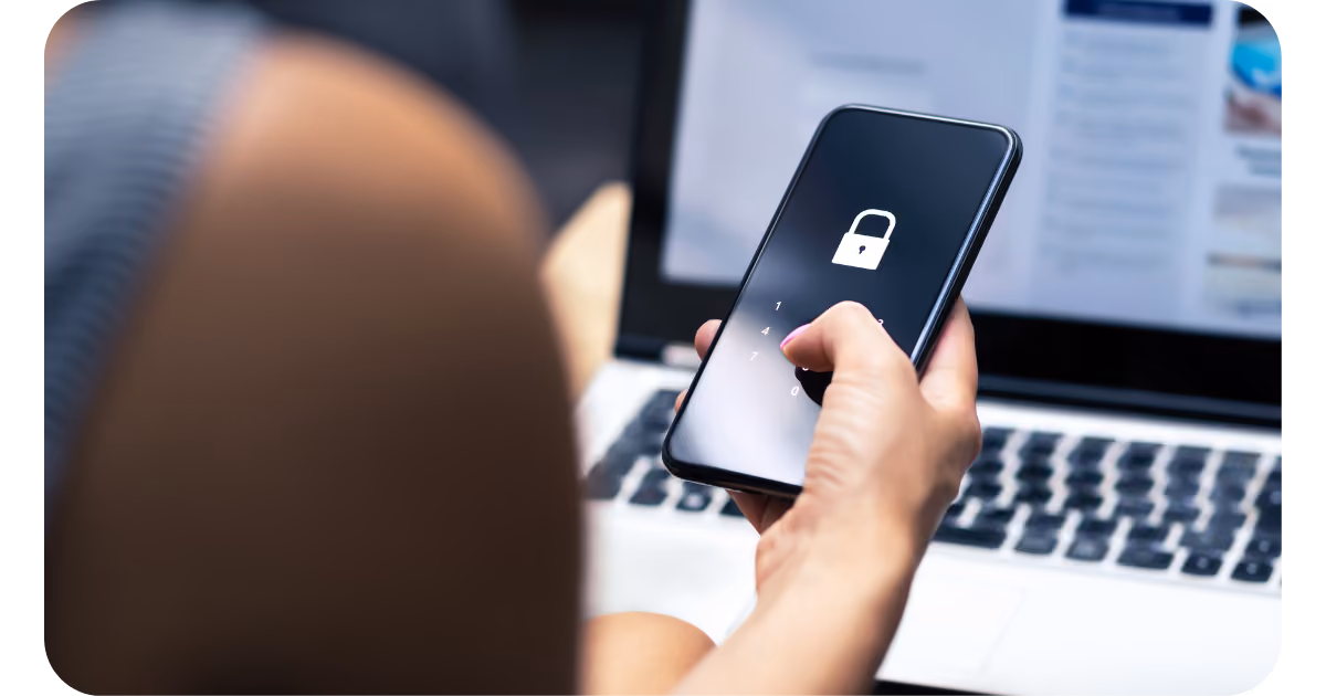 woman using phone with security lock screen while she uses laptop
