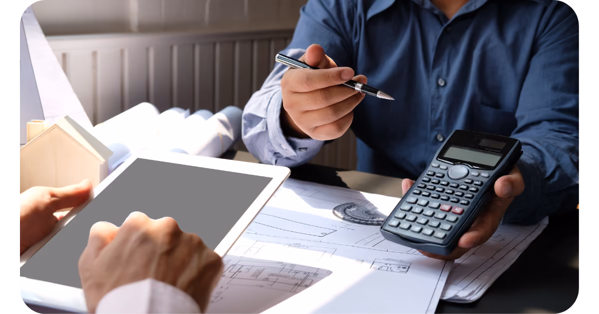 a person is using a calculator and a tablet while sitting at a desk