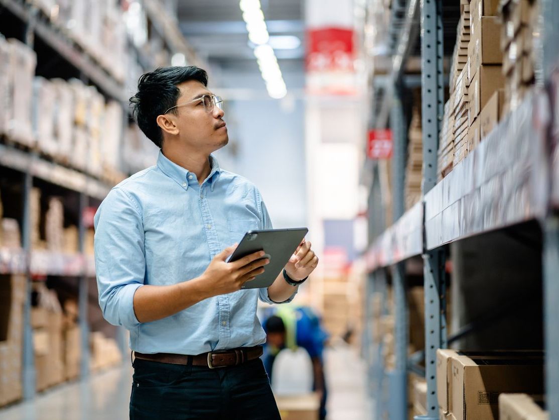 Warehouse manager using a tablet to check inventory in a warehouse