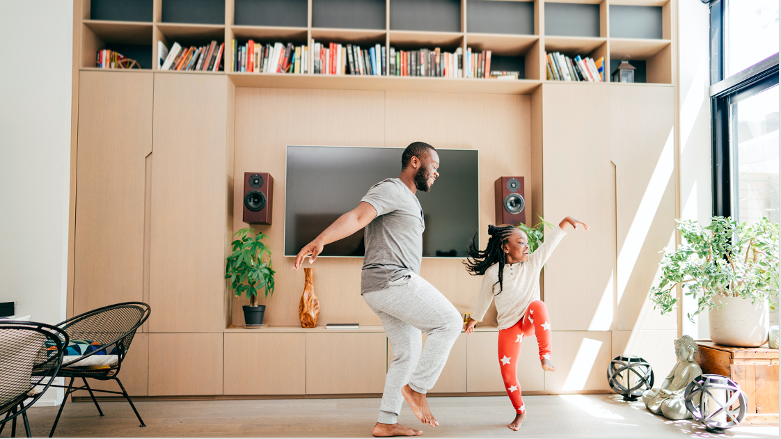 A Father dancing with their daughter indoors.