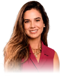 Smiling woman with long brown hair wearing a sleeveless maroon top and gold necklaces.