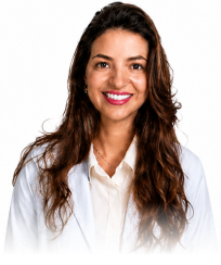Smiling woman with long curly brown hair wearing a white coat and beige blouse.