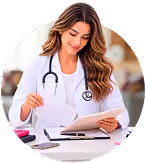 Female doctor with stethoscope reviewing medical documents at desk with tablet and phone.