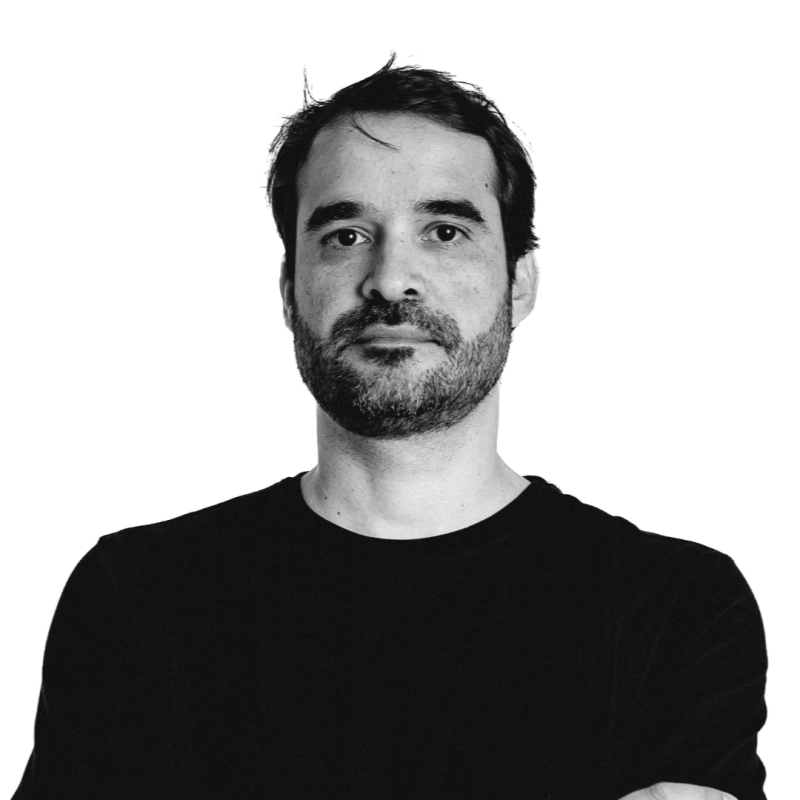 Portrait of a man with short dark hair and beard wearing a black shirt against white background.