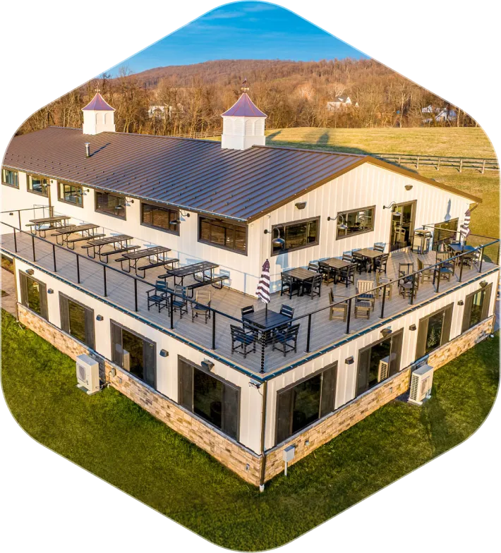 Two-story white building with rooftop patio furniture and purple-roofed cupolas in a rural area.
