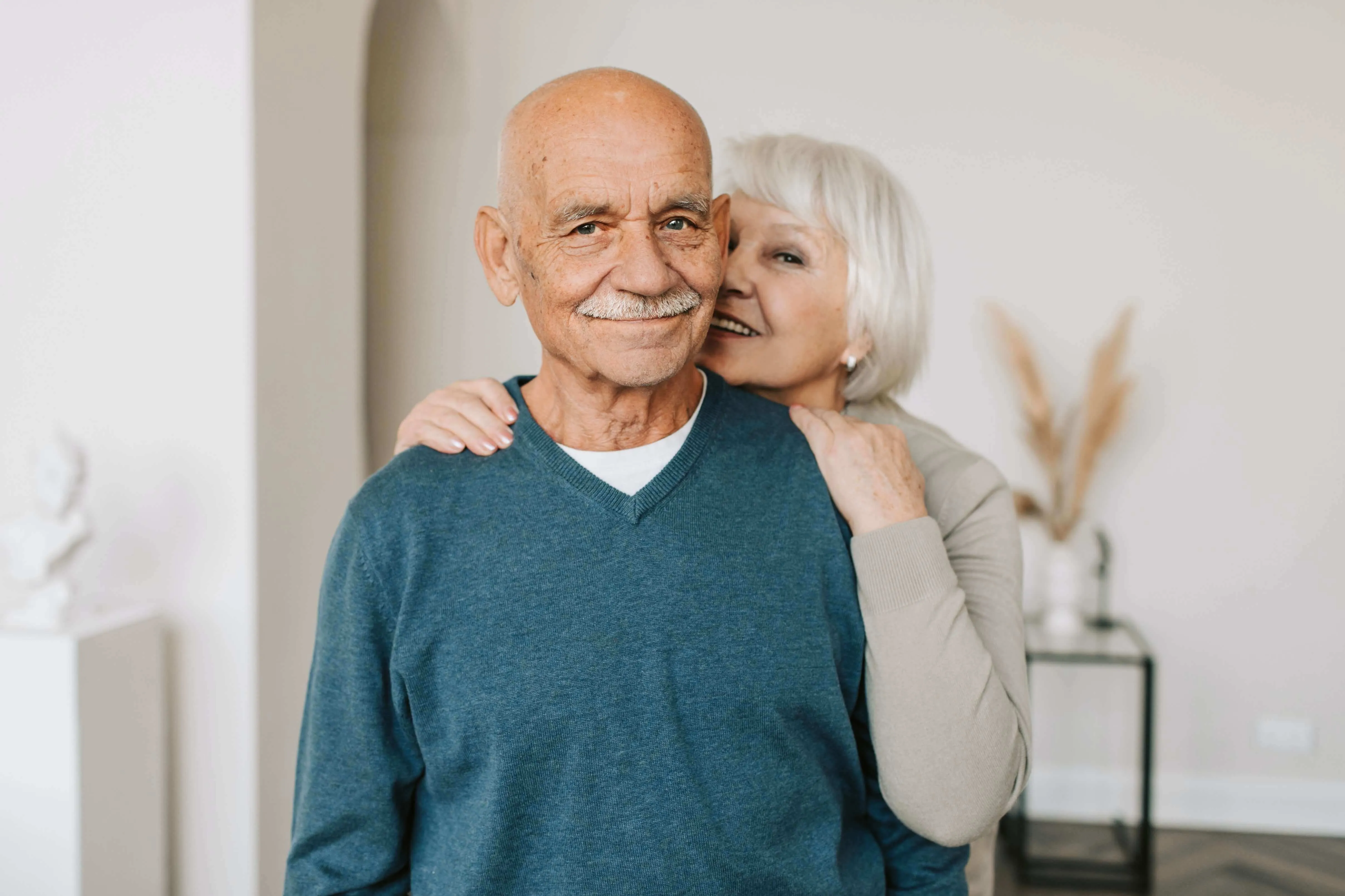 Aging woman whispering into aging man's ear
