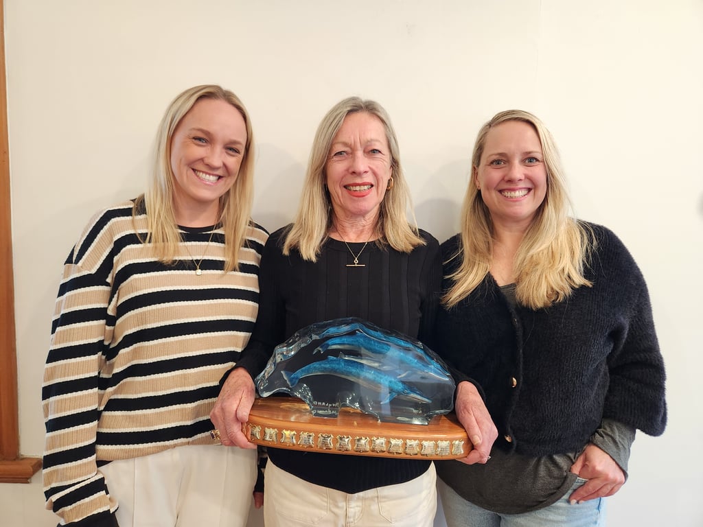 Des' wife Christine (centre) and daughters Anna and Emily proudly receive the award