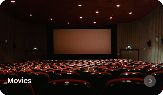 Movie theater with rows of red and black seats facing a large blank screen.