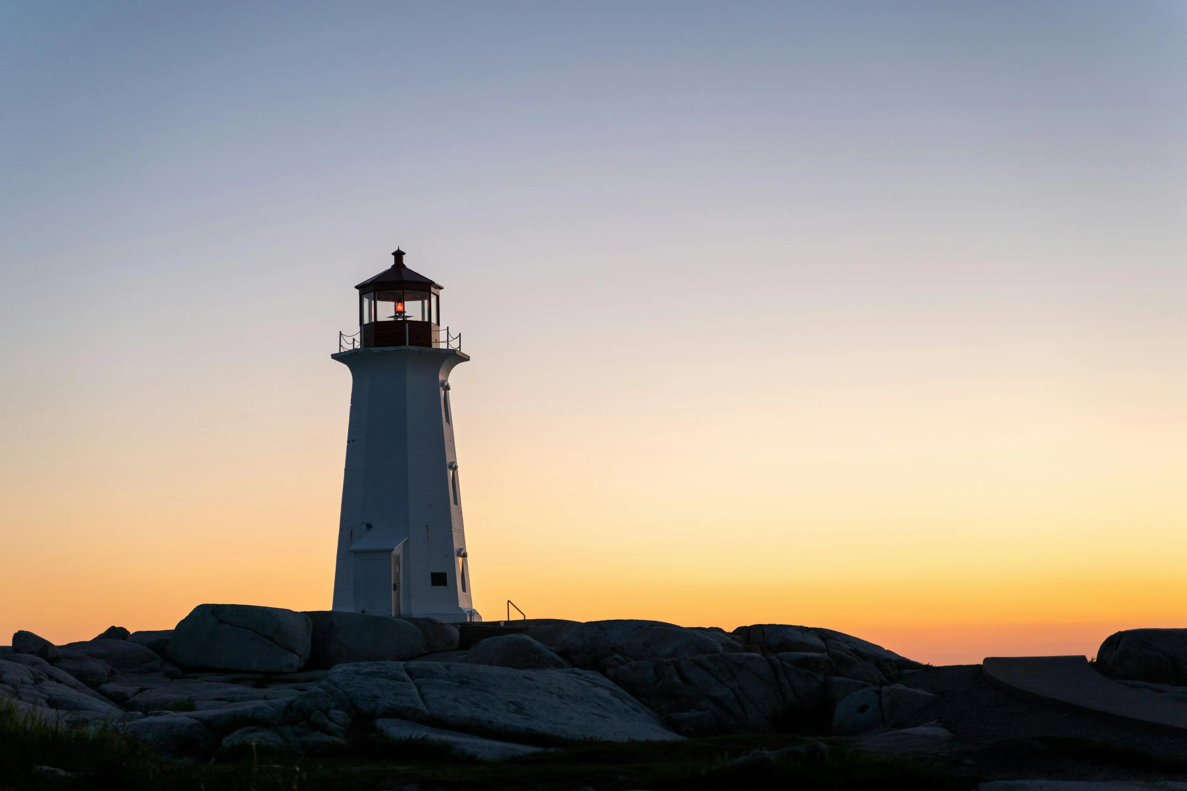 A lighthouse with the sun setting in the background