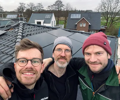 Gründerteam eines PV-Startups auf Ziegeldach mit frisch installierter Photovoltaikanlage.