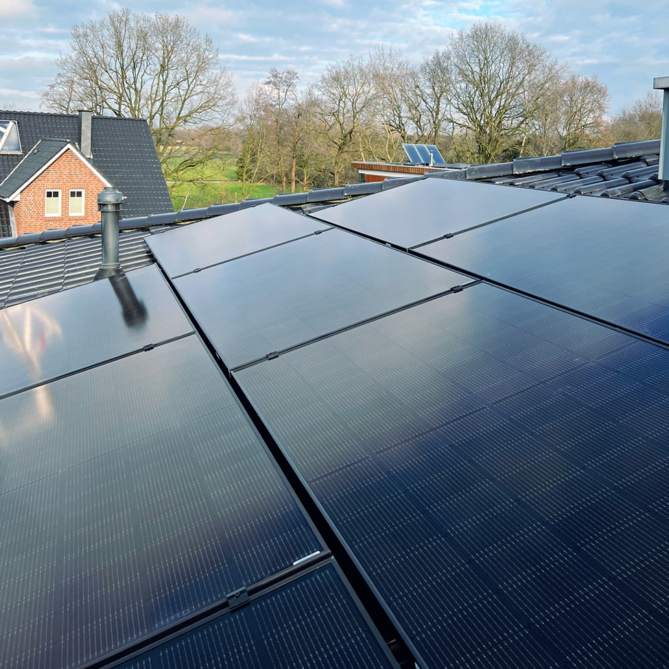 Photovoltaikanlage auf Ziegeldach eines weißen Mehrparteienhauses – optimale Flächennutzung für nachhaltige Stromerzeugung im Eigenheim.