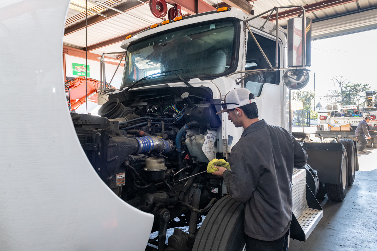 Technician performing diesel engine repair on a heavy-duty truck inside a service bay.