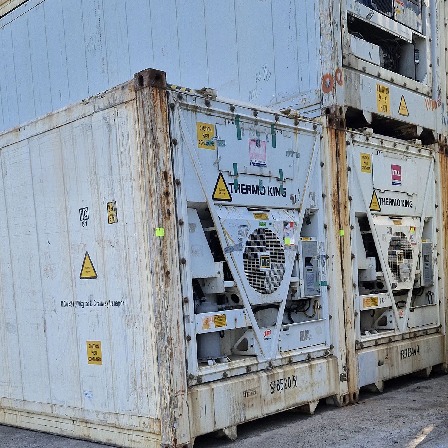 Zwei gestapelte, weiße Kühlcontainer mit Thermo King Aggregaten und sichtbar rostigen Ecken.