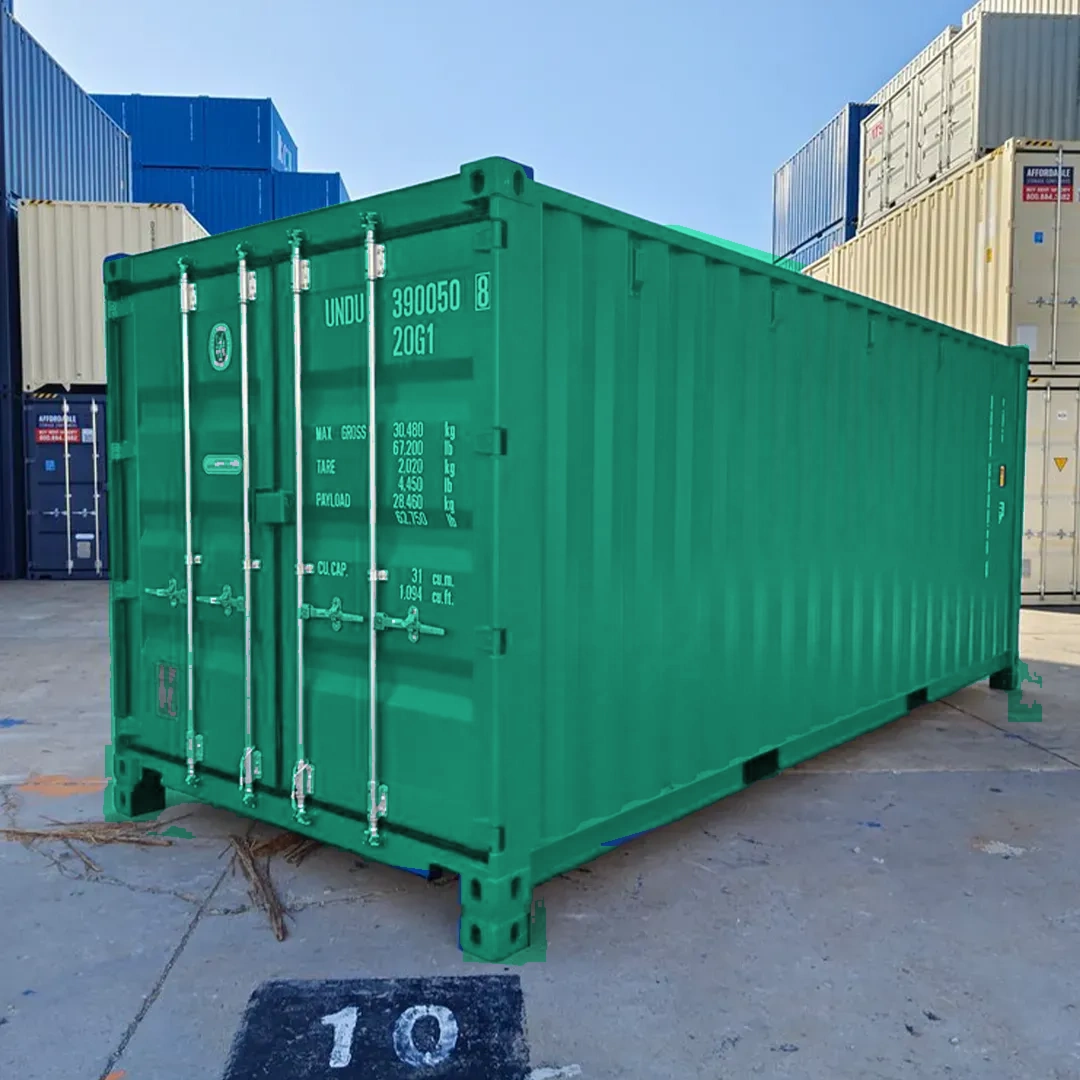 Moosgrüner Container auf Betonplatz mit anderen Containern im Hintergrund unter blauem Himmel.