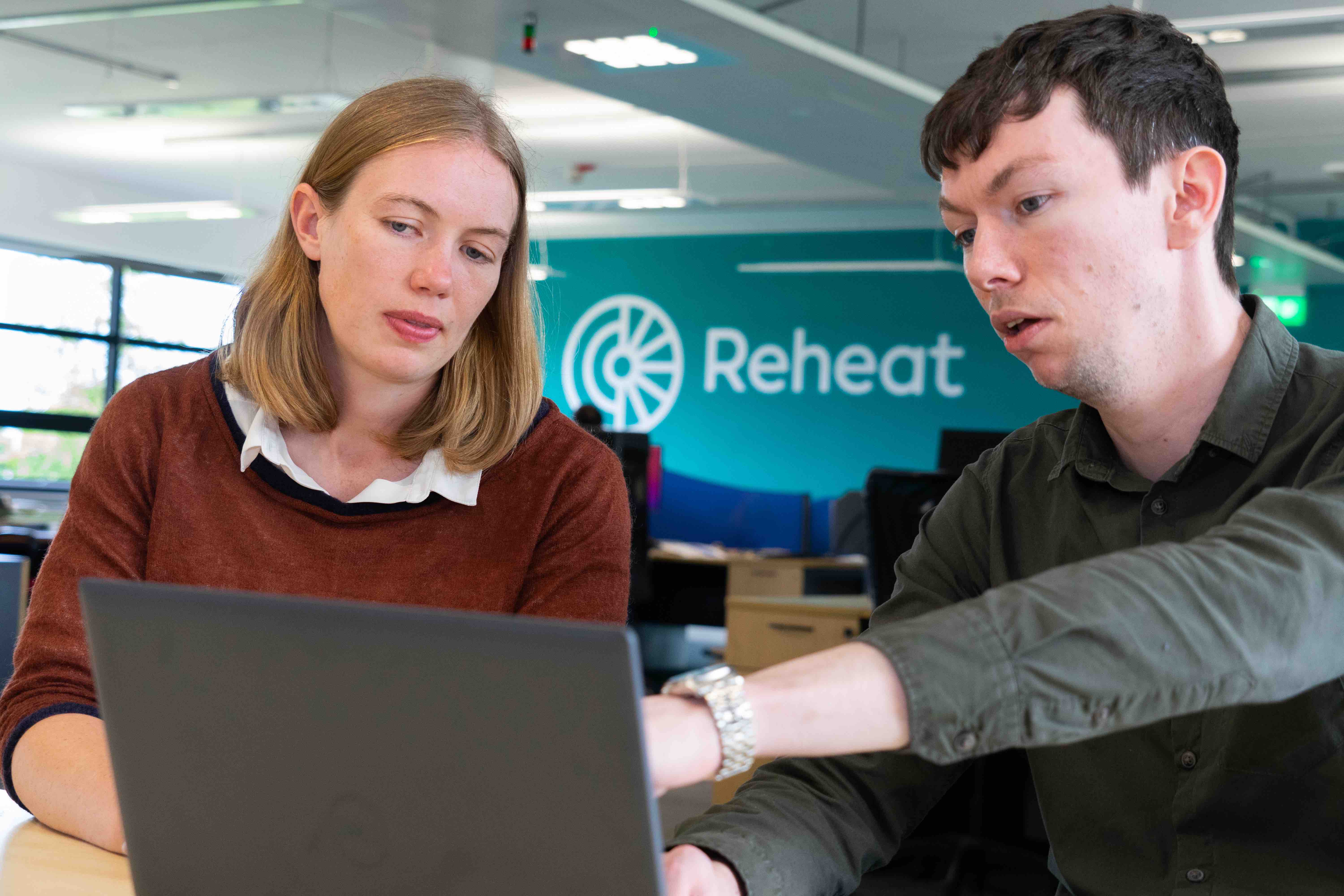 Two Reheat consultants looking at a project on a laptop.