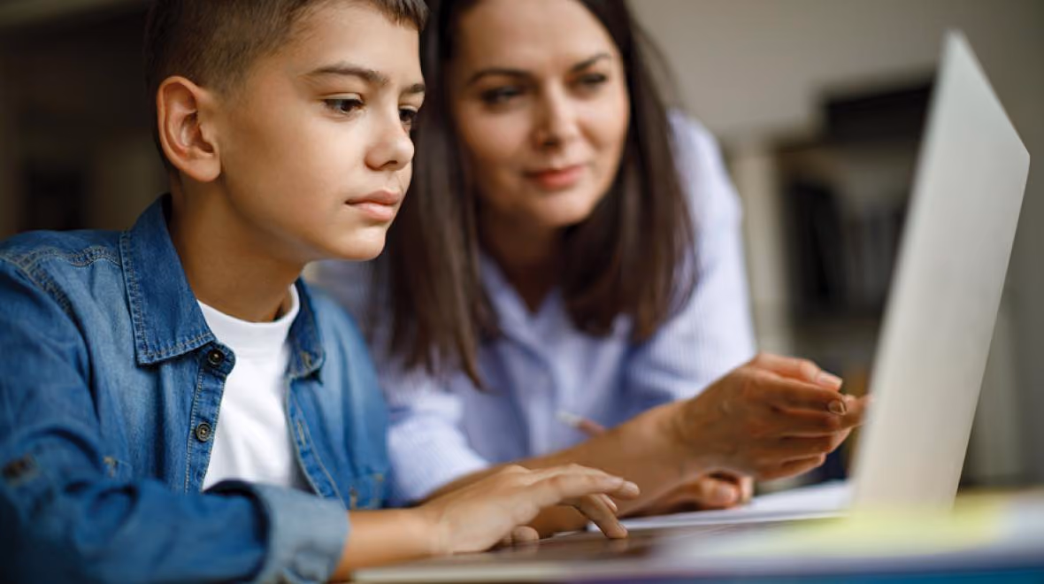 Una mamá y su hijo leyendo información en una computadora