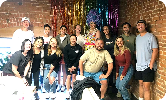 A group of people posing for a photo with a drag queen.
