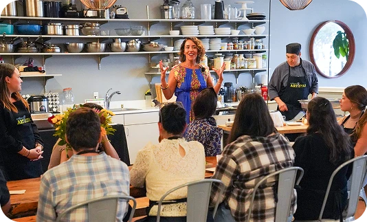 People sitting at a long table in a pottery studio