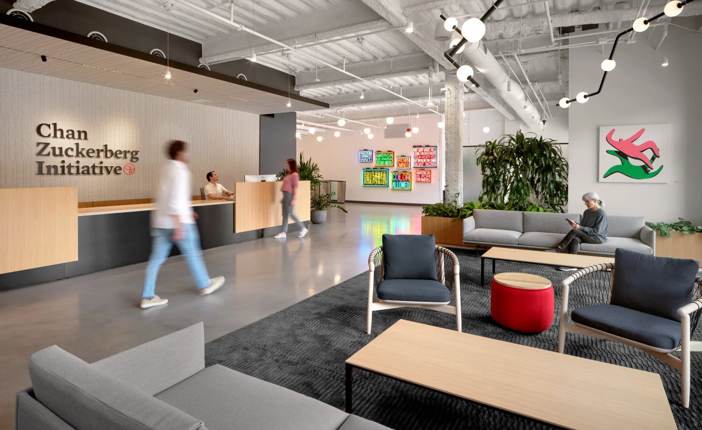 Modern office lobby with Chan Zuckerberg Initiative sign, seating area, and neon wall art in background.