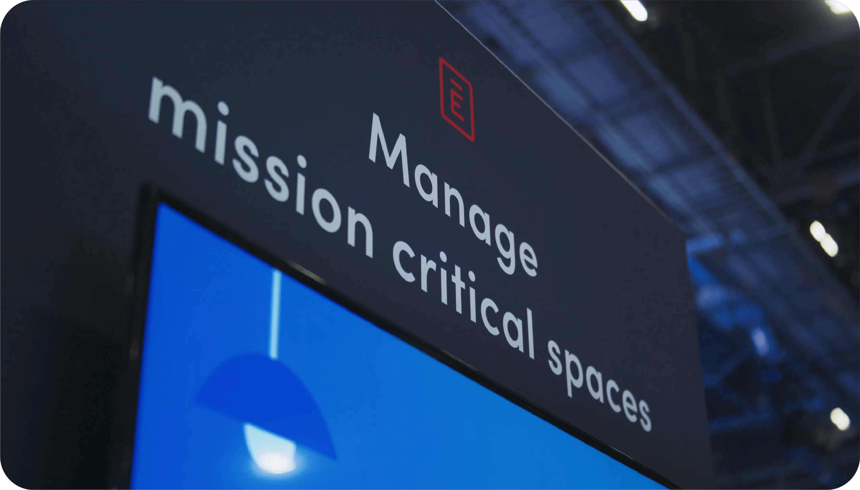 A sign above a screen displaying the text 'Manage mission critical spaces' with a red icon of a document above the text.
