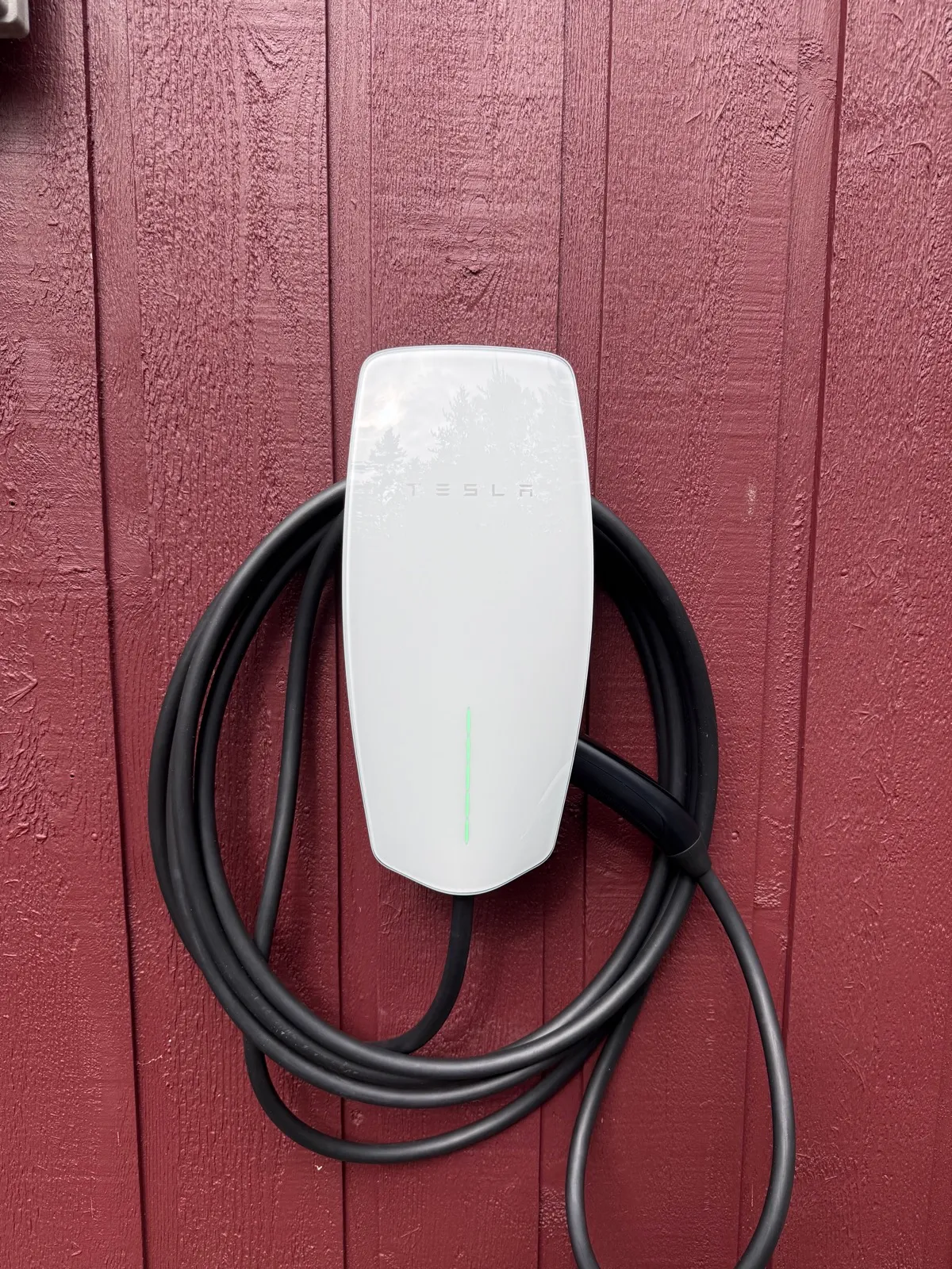 Tesla Wall Connector with its charging cable coiled around the unit.