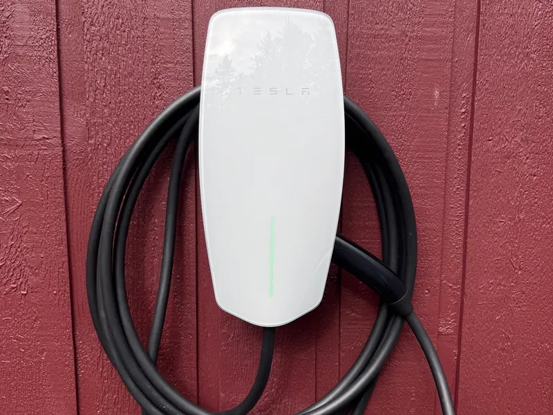 Tesla Wall Connector with its charging cable coiled around the unit.