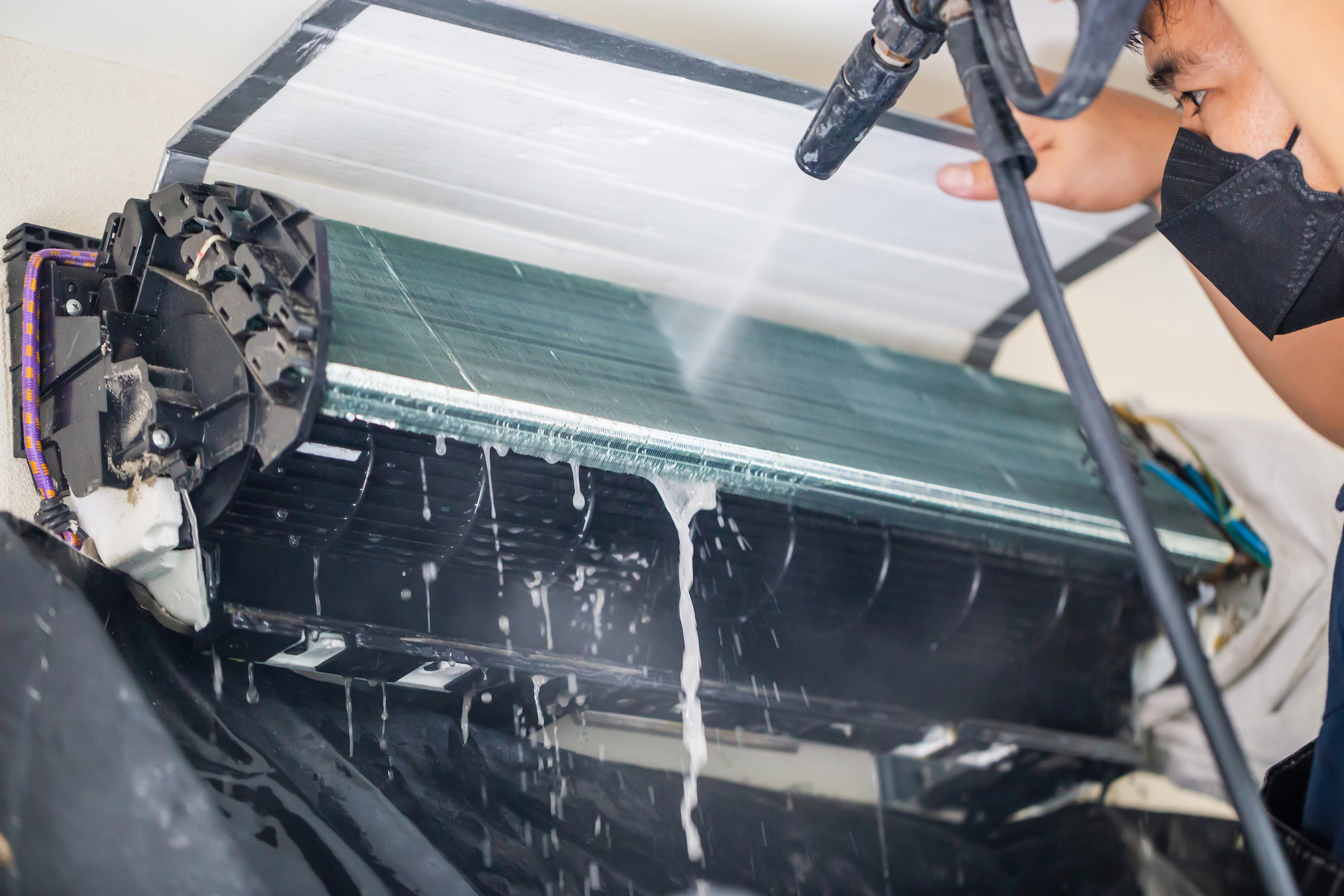 Male technician cleaning air conditioner indoors