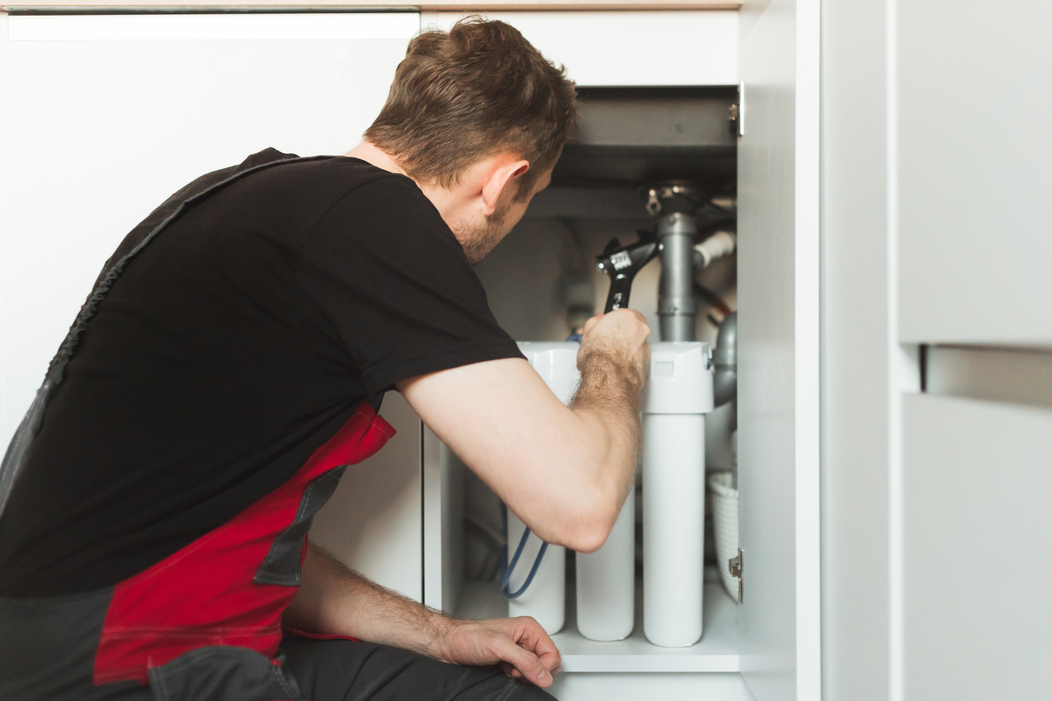 Our expert technician is hard at work fixing a leak under the sink. 