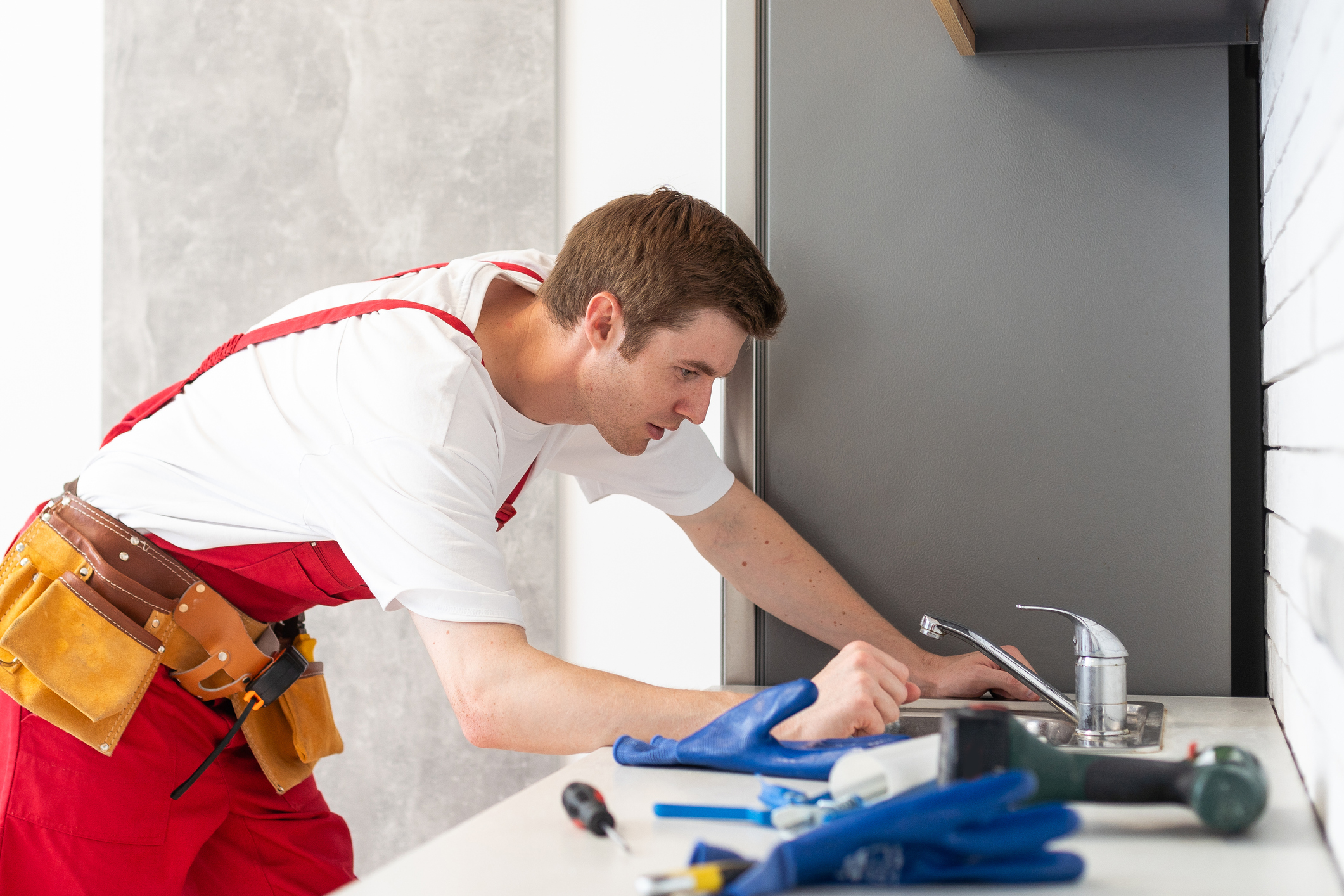 Plumber checking water flow from tap in kitchen