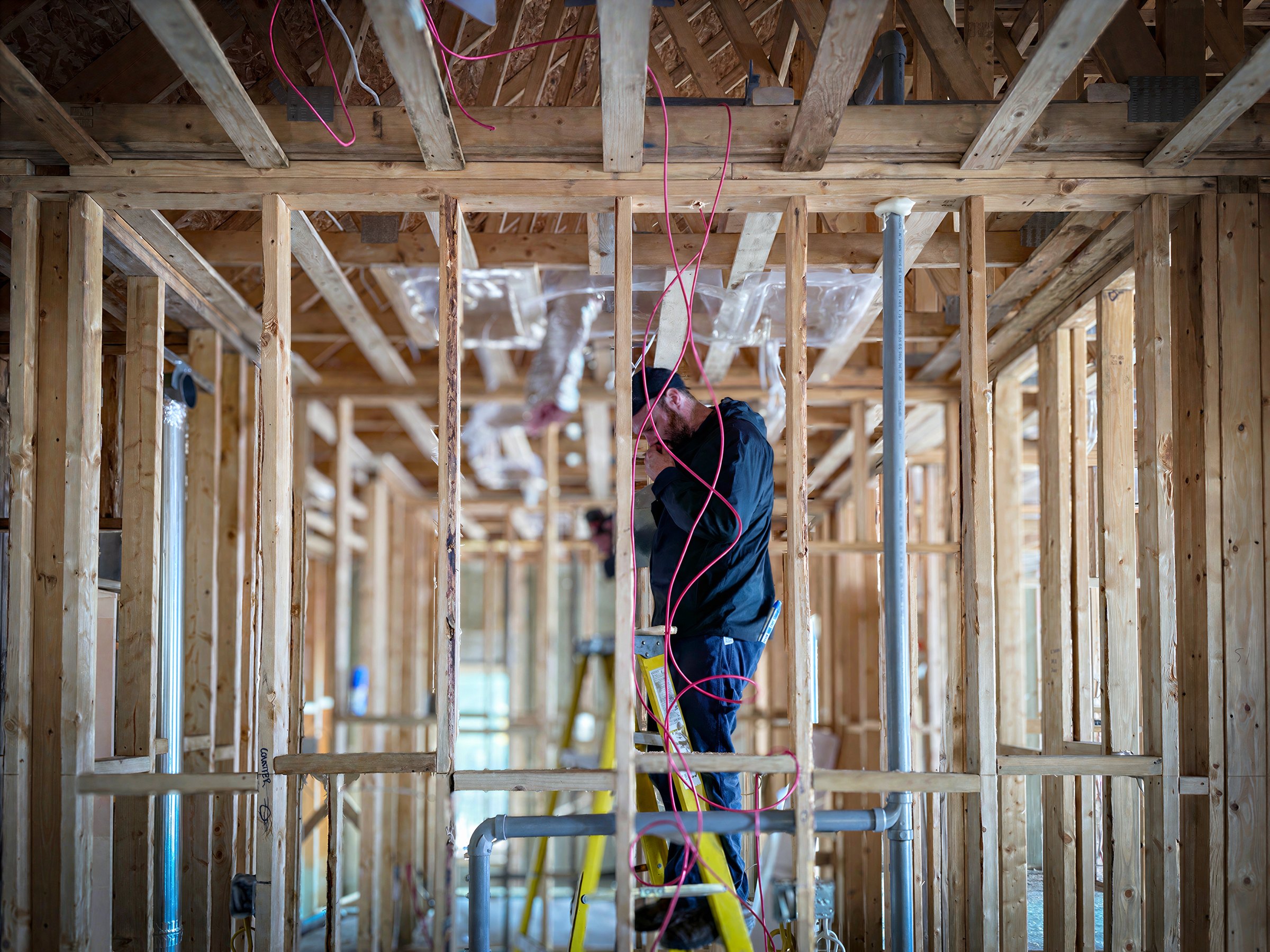 Electrician pulling new wiring through framing during a residential construction project