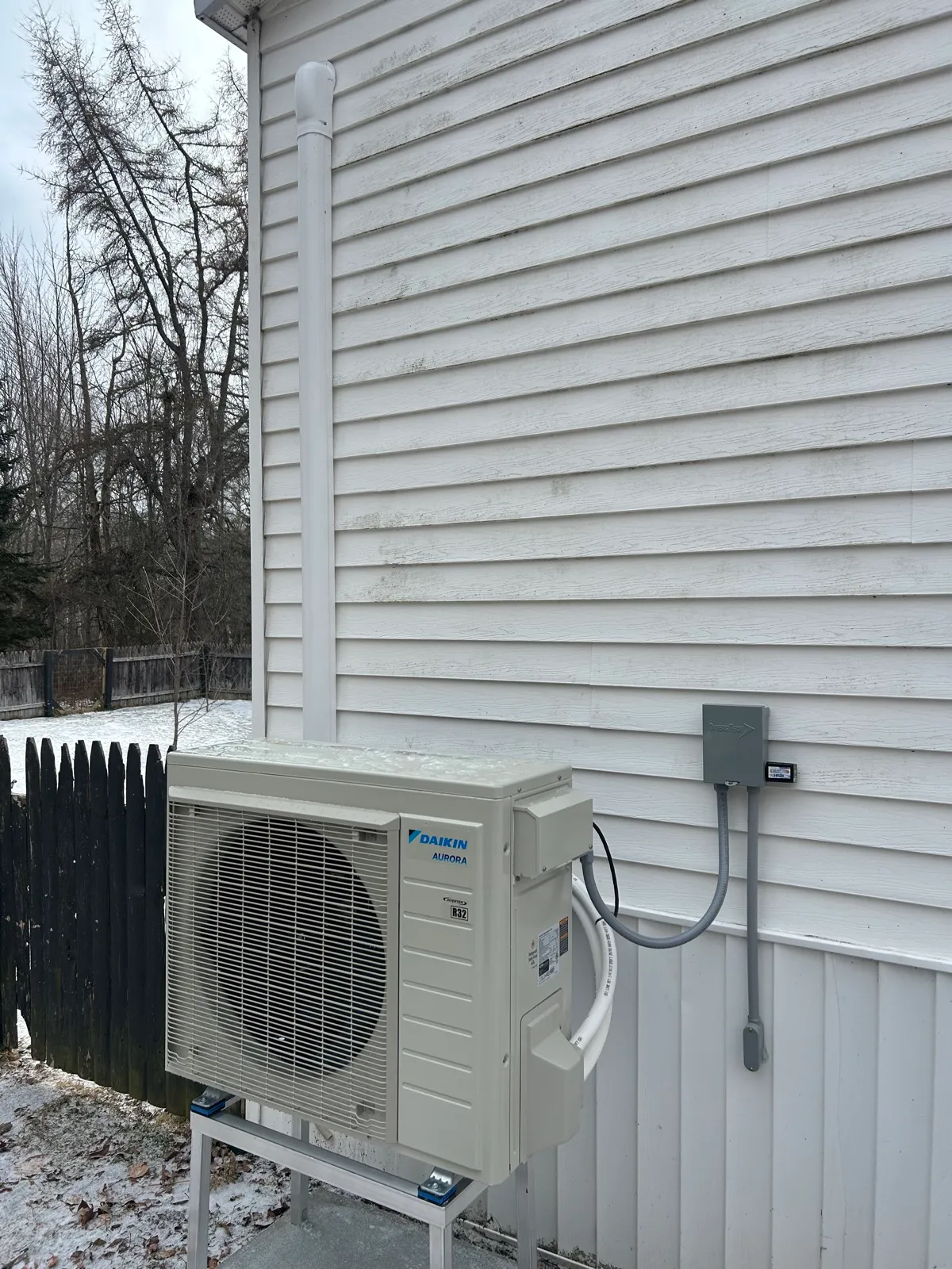 Daikin outdoor unit with disconnect, protected lineset and raised stand.