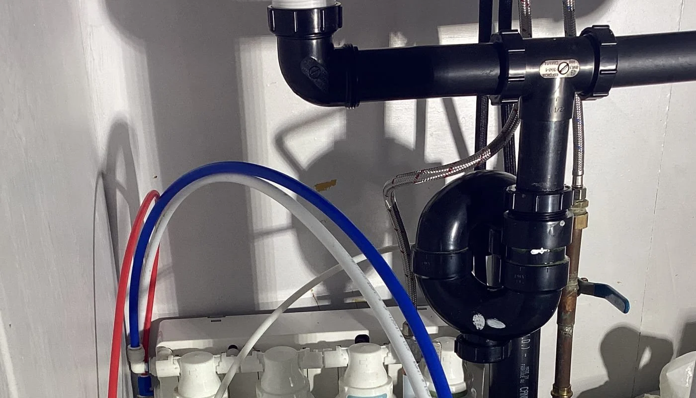 Accessible sink drain, trap and water connections inside a cabinet.