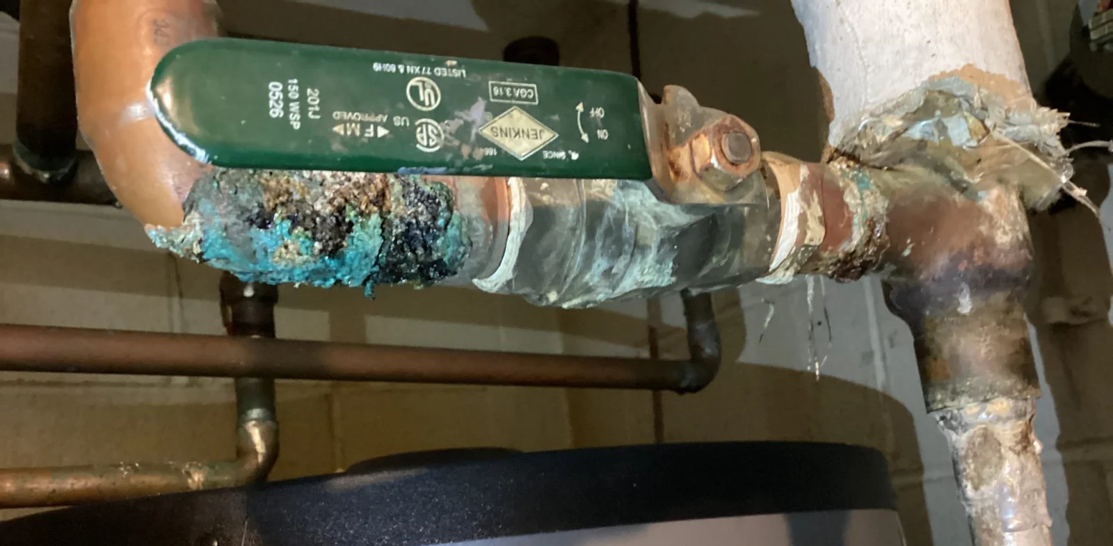 Corrosion and mineral buildup at an older copper-pipe shutoff connection.
