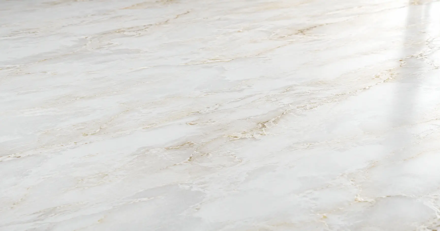 Close-up of Golden Dawn Quartz showing a white background with soft grey and warm gold veining