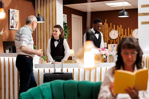Hotel staff assist guests while answering services handle 24/7 reservations and calls