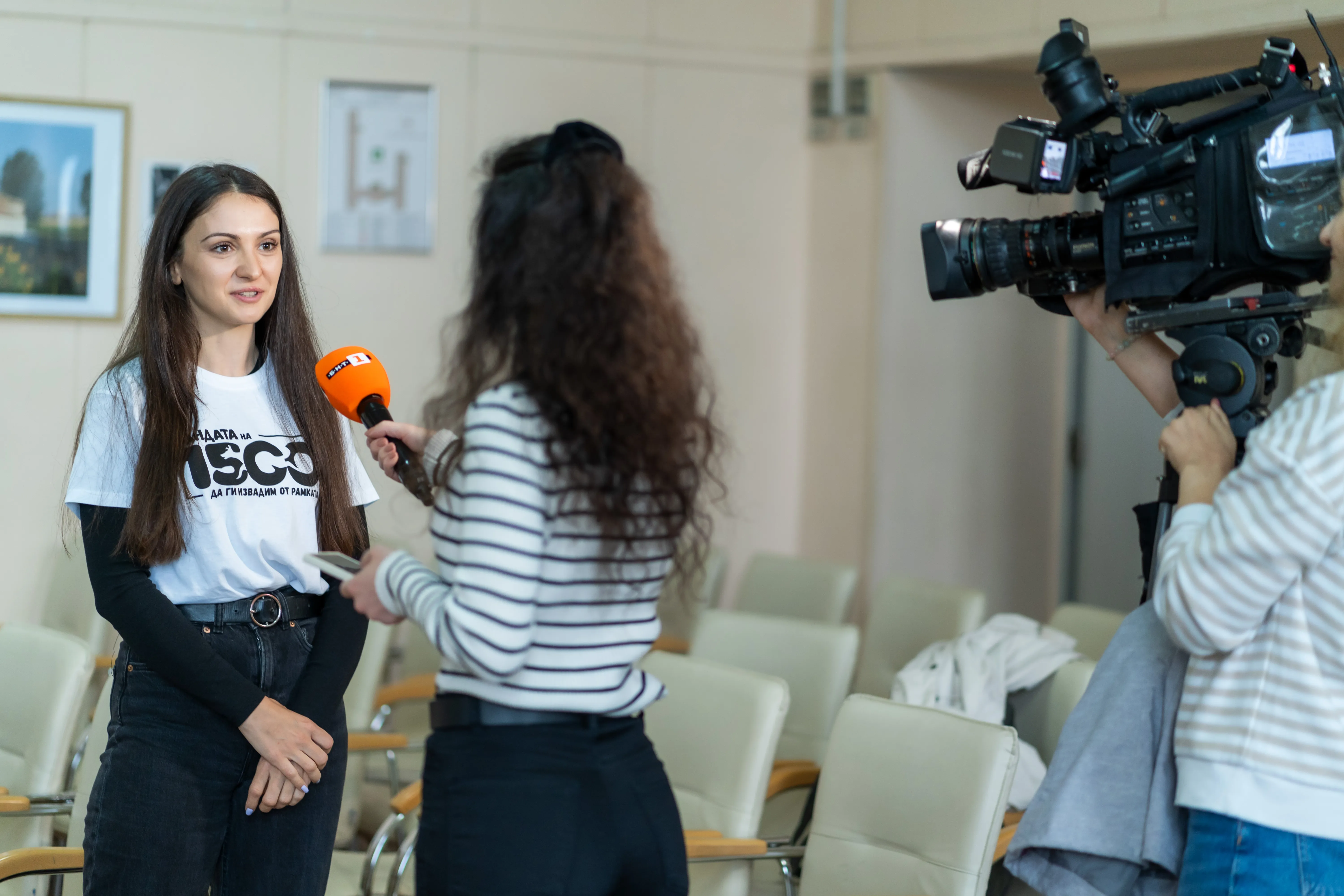 Доброволец на Бандата дава интервю пред репортерка. Камерата, която ги снима, е в десният ъгъл.