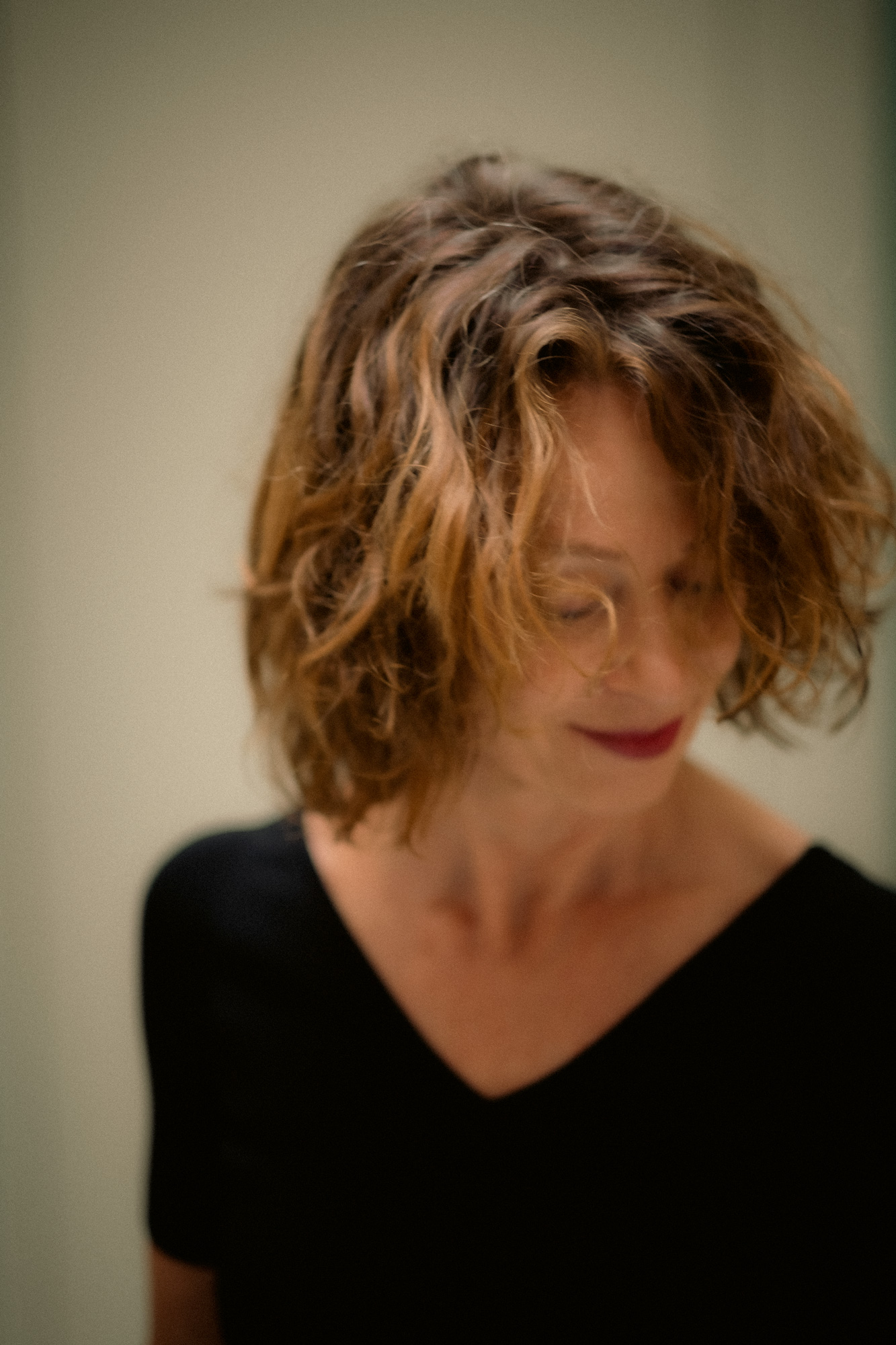 Whimsical close-up of Liesbeth Dillen in motion, with a soft smile and her head tilted down to the left