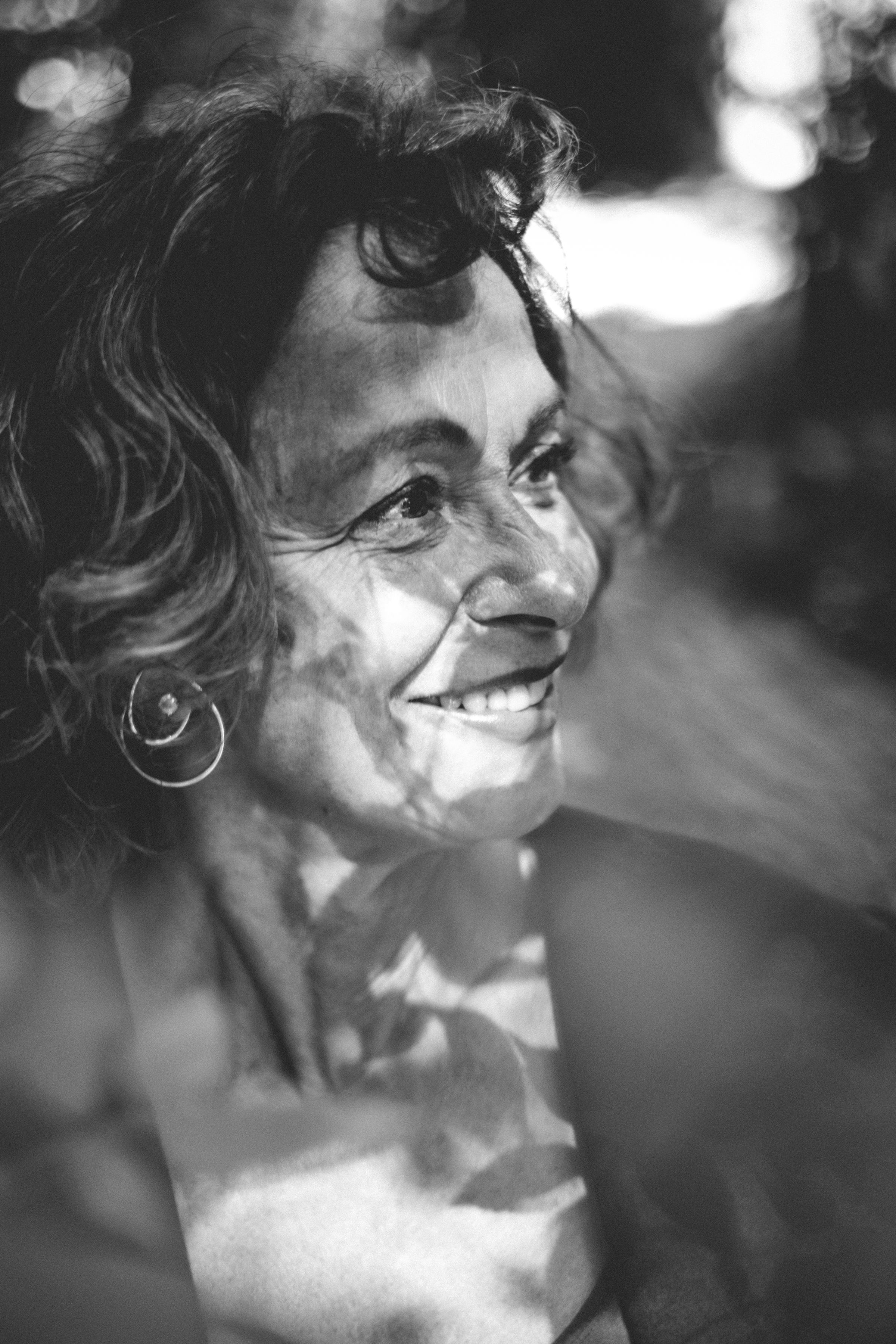 Black-and-white close-up of Liesbeth Dillen in the forest, with a huge smile, looking to the left