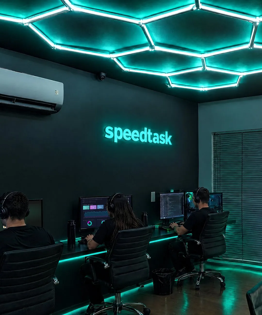 Sala de desenvolvimento da Speedtask, com teto em neon verde-água e o letreiro da marca