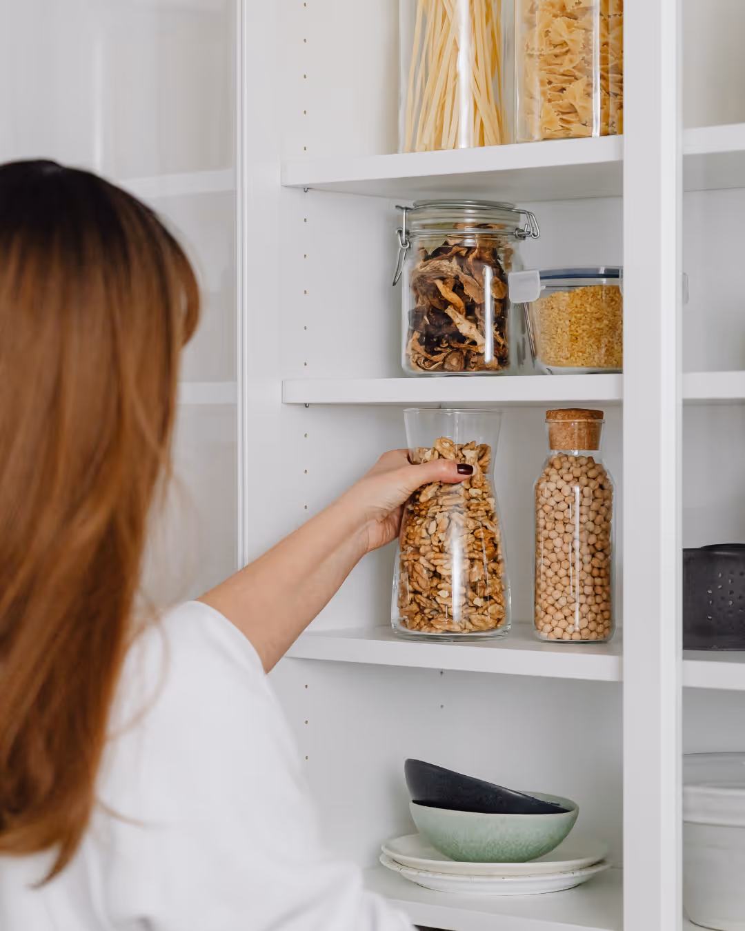 Woman storing food in patry