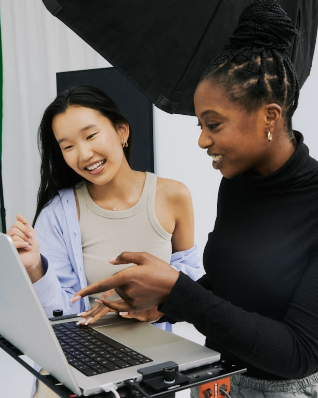 Aerial shot of several people collaborating at shared desk with laptops and notebooks