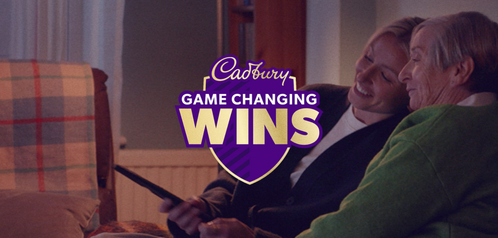 Hero image for Cadbury's 'Game Changing Wins' the logo is in the centre, in the background is two people in a cadid shot.